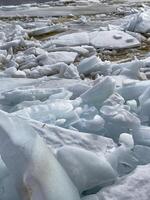 Close-up view of melting ice and snow revealing water and rocks beneath, a sign of seasonal change. photo