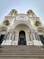 A stunning low-angle view of an Orthodox cathedral's entrance, adorned with intricate mosaics and golden domes, under a clear sky. photo