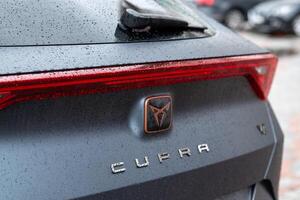 Kyiv, Ukraine. April, 2024. The Seat Cupra logo on a car in gray close-up with water drops photo