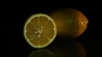 Two delicious beautiful lemons lie on a dark background. Slice of lemon. video