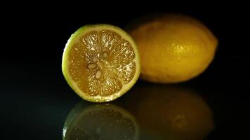 Couper et entier juteux citrons mensonge sur une foncé miroir table dans le foncé video