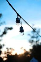 Equipped and electrical with light bulbs is shining and hanging in twilight of sunset before night photo