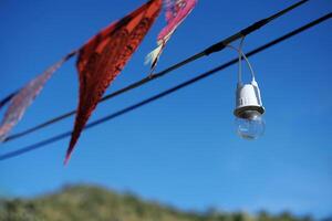 equipado y eléctrico con ligero bombillas es colgando en el viento y luz de sol en azul cielo foto