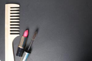 Wooden comb, lipstick and mascara on a black background with space for text. mockup photo