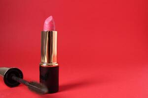 rosado lápiz labial y ojo cepillo en rojo antecedentes con espacio para Copiar espacio texto. moderno maquillaje foto