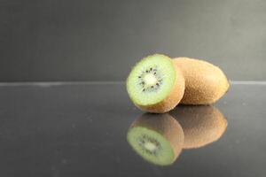 Whole and half fruit kiwi berries lie on a black background with a copyspace photo