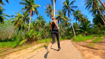 Woman Runs Along a Scenic Road With Palm Trees on Tropical Island, Thailand video