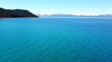 aereo Visualizza al di sopra di lago Tahoe, Nevada, noi. blu acqua di un' grande lago nel California. montagne coperto con neve nel il nazionale parco su il altro lato di il lago video