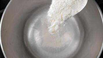 Flour is poured from a spatula into a metal pan. Close-up of flour being poured into an empty pan video