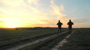 oorlog Oekraïne Rusland. oekraïens leger zonsondergang patrouille in de platteland, silhouetten van twee soldaten patrouilleren een landelijk pad Bij zonsondergang. video