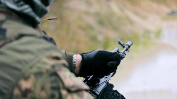 A military shooter discharges a machine gun from ammunition. Close-up hand pulls the shutter of the machine and releases the cartridge case from the clip. video