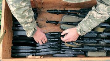 The military puts ammunition in a box. Sorting ammunition and submachine guns in a wooden box. Military ammunition. video