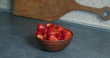 Home kitchen. A man puts juicy strawberries into a deep clay plate video