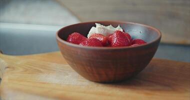 Home kitchen. Red strawberries with cream in a clay plate on the table video