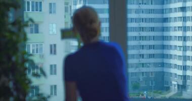 huis schoonmaak. blond meisje wast ramen in een appartement met een spons Aan een zonnig dag video
