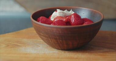 Home kitchen. Strawberries with cream in a clay plate on a wooden cherry board video