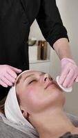 a com experiência cosmetologista massagem terapeuta executa uma relaxante facial massagem para a cliente para aliviar tensão, promovendo profundo relaxamento e hidratação, deixando seu pele atualizado e radiante. video