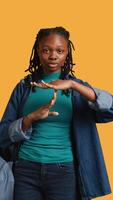 Vertical Portrait of assertive woman asking for timeout, doing hand gestures, feeling fatigued. Unhappy girl doing vehement pause sign gesturing, wishing for break, studio background, camera B video