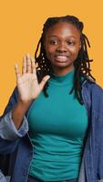 Vertical Assertive african american woman doing stop hand gesture and talking. Annoyed girl doing firm halt sign gesturing, wishing to end concept, isolated over studio background, camera A video