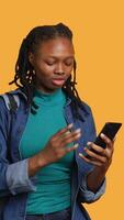 Vertical Upset african american woman arguing with friends during teleconference meeting on smartphone, studio background. Annoyed girl fighting on mobile phone videocall with mates, camera A video