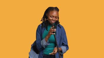 African american motivational speaker talking in microphone, addressing audience, holding speech, studio background. Inspiring woman using mic to present life lectures, camera A video