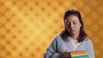 agotado mujer bostezando, participación pesado apilar de libros necesario para colegio examen, estudio antecedentes. estudiante anhelo para dormir, cansado de aprendizaje desde académico libros de texto, cámara un video