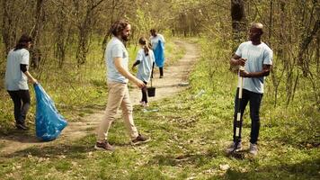 equipo de clima cambio activistas plantando verde arboles y semillas en un bosque ambiente, uniendo a conservar ecosistema. voluntarios instalando plantas en el suelo, nutrir verdor. cámara b. video