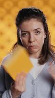 Vertical Disappointed woman bashing book, showing thumbs down hand sign, isolated over studio background. Upset bookworm dissatisfied with new novel, giving negative review, camera B video