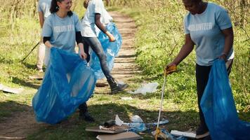 gruppo di diverso volontari raccolta sciocchezze a partire dal il boschi e raccolta differenziata nel un' spazzatura disposizione Borsa, rifiuti pulire responsabilità. ecologia attivisti raccolta su spazzatura e plastica sciupare. telecamera un. video