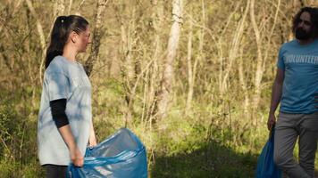 Freiwillige Gruppe vorbereiten zu sammeln Müll und Müll von das Wald, Recycling Plastik Abfall und andere Müll im Taschen. Umwelt Aktivisten schützen das Natur durch pflücken oben Müll. Kamera a. video