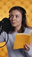 Vertical Voice actor looking to producer off camera to know when to start narrating book, producing audiobook. Narrator doing counting on fingers gesturing before starting digital recording of novel, camera B video