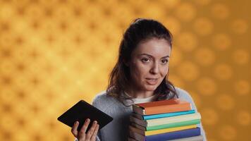 femme débattre entre physique livres et ebooks sur liseuse, isolé plus de studio Contexte. rat de bibliothèque comparant papier des romans et numérique Littérature sur tablette, La technologie concept, caméra une video