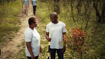 Portrait of a couple volunteering to plant trees and collect trash from the woods, hold shovel and showing devotion for ecological justice. Environment activists fight nature conservation. Camera B. video