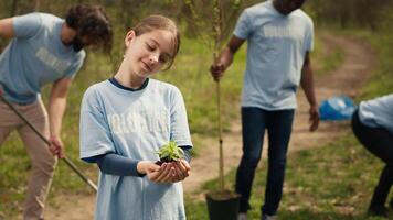 pequeno menina segurando uma pequeno verde brotar com natural solo dentro ordem para preservar floresta habitat e proteger a ecossistema. criança crescendo acima com uma dedicação para de Meio Ambiente proteção. Câmera uma. video