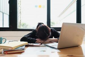 Stressed business woman hard working until morning and tired and sleep at table in office while project deadlines. finance, account, tax, audit concept. photo