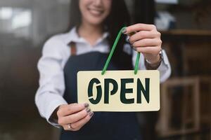 a su café comercio, sonriente pequeño negocio propietario torneado alrededor abierto tienda espalda a abierto el tienda después COVID-19. foto