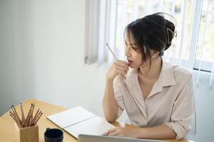 Asian Business woman sitting in office with laptop computer on wooden desk photo