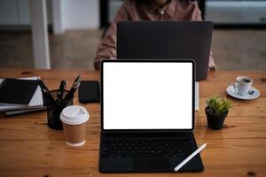 Mockup image of black tablet with keyboard and blank white screen with business team working at background on wooden desk. photo