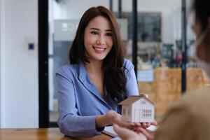 A real estate agent demonstrates the House model to clients interested in purchasing house insurance. The concept of home insurance and property. photo