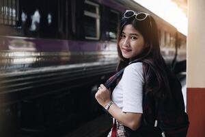 Image of a woman with a rucksack standing at a train station waiting to board a train. concept of solo travel. photo