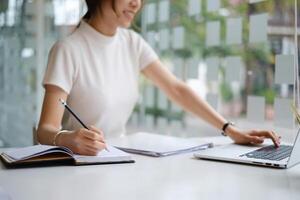 Young female college taking notes and using highlighter. Focused student in online class room. Authentic Education concept. photo