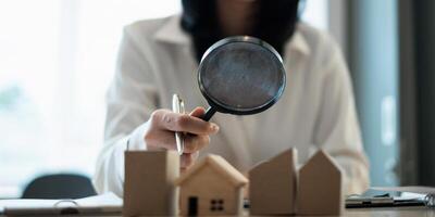A woman holding magnifying glass and checking house model .Real Estate House Appraisal And Inspection concept. photo