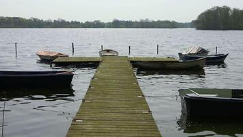 une jetée avec une peu aviron bateaux sur un idyllique Lac dans le Soleil. video