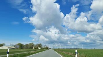 View from a moving car onto a country road with a wind farm on the side. video