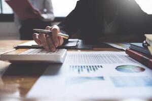 Project management team updating and calculating financial chart on paperwork, two business people in office. photo