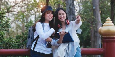 Two Young students from university enjoying excursion in park and pointing something when them interesting. Study, education, university, college, graduate concept. photo