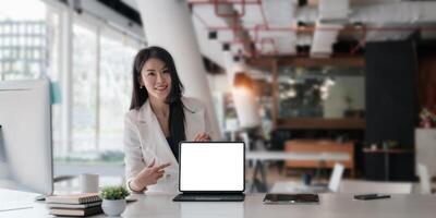 Business woman holding and pointing at digital tablet with blank screen in coffee shop. photo