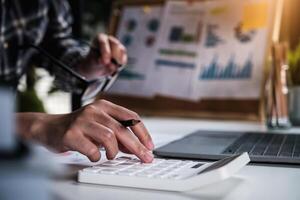 Project management updating and calculating financial chart on paperwork. work from home concept. photo