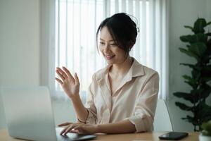 Asian Business woman sitting in office with laptop computer on wooden desk. photo