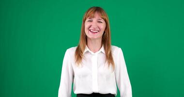 Happy beautiful red-haired woman in white clothes smiles and says something on a green background. video